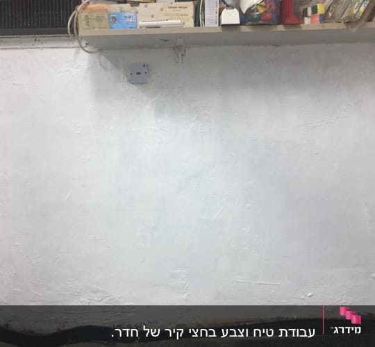 קיר צבוע בלבן עם מדף מעליו